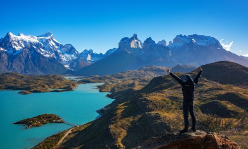 Hiker at mirador condor enjoying amazing view of Los Cuernos rocks and Lake Pehoe in Torres del Paine national park, Patagonia, Chile
